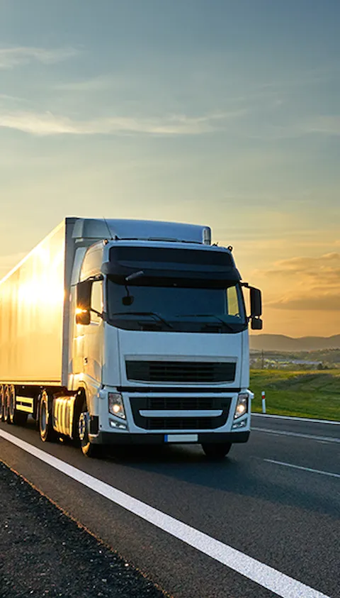 Vrachtwagen op een weg met zon op de achtergrond