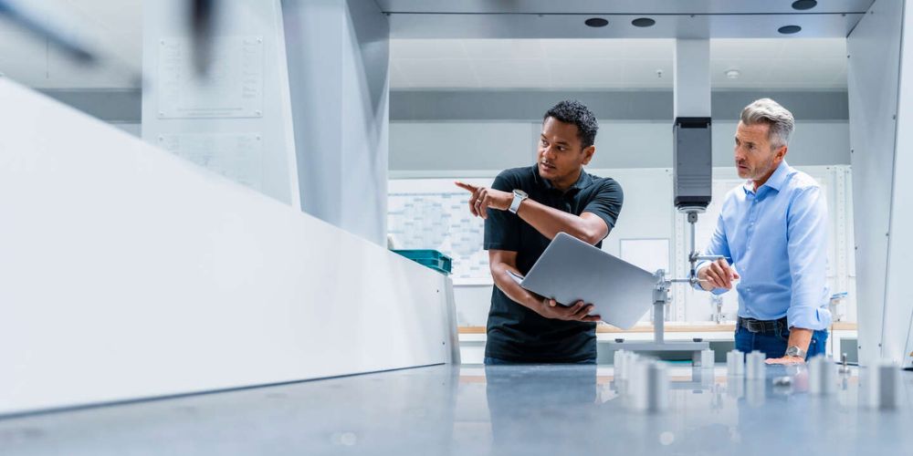 Ingenieur met laptop, aangewezen door een zakenman in een fabriek